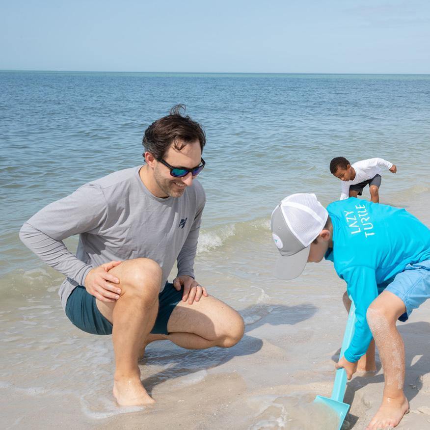 Man wearing Ocean Sun Safe Long Sleeve playing on beach with kids